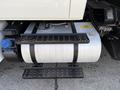 Close-up of a silver fuel tank mounted on a truck's chassis with black brackets and a step for access