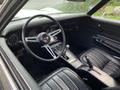 Interior of a 1972 Chevrolet Corvette featuring a black leather seat dashboard and steering wheel with a central gear shifter and various gauges visible