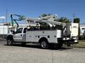 A white 2016 Ford F-550 service truck with a utility bed and a cherry picker mounted on the back