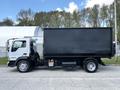 A 2009 Ford LCF 550 with a white cab and a large black box truck body parked on a driveway