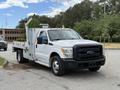 A 2015 Ford F-350 SD truck with a white body and utility bed featuring a crane attachment on the rear