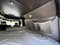 The interior of a 2017 Mercedes-Benz Sprinter featuring a bed with bedding and wall-mounted storage pockets