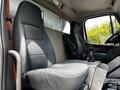 Interior view of the driver's seat and passenger seat in a 2010 Freightliner M2 106 with fabric upholstery and a gear shift lever in the center console