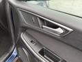 Interior door panel of a 2017 Ford Edge featuring control buttons for windows and locks with a sleek metallic finish and textured black material