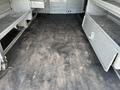 Interior view of a 2016 Ford Transit van showing empty cargo space with rubber flooring and shelving units along the sides