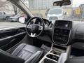 Interior of a 2017 Dodge Grand Caravan featuring a black leather steering wheel dashboard and center console with controls and storage compartments