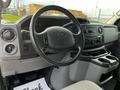 Interior view of a 2014 Ford Econoline showing the steering wheel dashboard controls and center console with cup holders