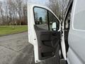 White 2023 Ford Transit van with the driver's side door open showing the interior door panel and window