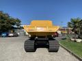 A 2022 TerraMac Tracked Dump with a yellow body and large rubber tracks positioned in the foreground facing away from the viewer