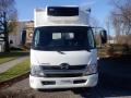 A front view of a white 2015 Hino 195 truck with a refrigeration unit on top and a simple grille design