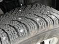 Close-up of a winter tire showing deep treads and metal studs designed for enhanced traction on ice and snow