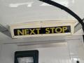 A sign that reads NEXT STOP mounted on the interior ceiling of a 2018 Chevrolet Express van