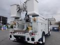 A white 2009 International 7400 truck equipped with an aerial lift system and various hydraulic components mounted on the back