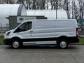A 2023 Ford Transit van in white with a low-profile design and black accents parked on the street