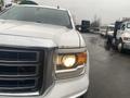 A 2015 GMC Sierra 1500 with a white exterior and prominent grille showcasing its headlights and hood