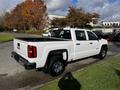 A white 2017 GMC Sierra 1500 pickup truck with a crew cab and chrome wheels parked on a street