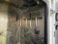 Two metallic hooks are mounted on a silver metal partition inside a vehicle compartment