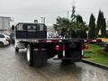 A 2011 International DuraStar 4300 flatbed truck with a black metal frame and red and white reflective stripe along the sides