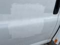 A 2016 Chevrolet Express van with a section of its side door partially covered in white paint, showing some water droplets on the surface