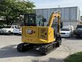 A yellow 2022 Caterpillar 306 excavator with a cabin and tracks positioned on a concrete surface
