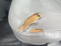 A close-up of a torn leather seat in a 2004 Ford Econoline showing exposed padding and wear damage
