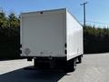 White box truck with a flatbed and no visible markings parked with its rear facing the viewer
