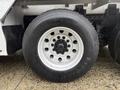 A close-up of a 2007 Freightliner FLD120 truck tire featuring a white rim with multiple holes and a black tire tread clearly visible