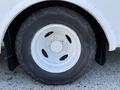 Close-up of a wheel and tire of a 2016 Ford Econoline featuring a white rim and rugged tread design