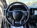 Steering wheel of a 2018 Ford F-150 with controls for audio and cruise settings visible along with the Ford logo in the center