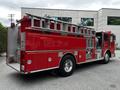 A red 1991 Sutphen Deluge fire truck featuring a ladder, multiple compartments and shiny chrome details parked with its rear visible