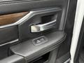Close-up of the interior door handle and control panel for power windows in a 2024 RAM 5500 featuring leather and wood accents