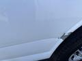 Close-up of a 2013 Chevrolet Express showing a dent and some paint scraping on the passenger side door with a part of the tire visible in the frame