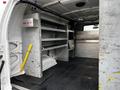 Interior of a 2011 Ford Econoline with metal shelving units and a yellow first aid kit visible on the floor