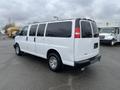 A 2012 Chevrolet Express van with a white exterior and chrome wheels parked at an angle showing its rear and side features