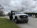 A 2021 Ford F600 truck with a flatbed and a white cab parked on a street