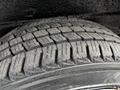 Close-up of a worn tire with deep treads and visible dirt indicating use from a 2020 Nissan NV200