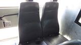 Two black vinyl seats inside a bus, with a cup holder between them