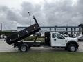 A 2021 Ford F600 truck with a black dump bed elevated at an angle showing its cargo area and a cab designed for construction or hauling purposes