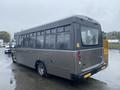 A 2017 Chevrolet Express bus with a gray body and large windows parked at an angle with a low profile design