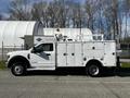 A white 2018 Ford F-550 utility truck with a service body and an amber beacon light on the roof