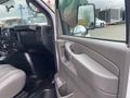 Interior view of a 2014 Chevrolet Express showing the driver's side with a gray door panel and a reflection in the side mirror