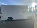 A 2017 Mercedes-Benz Sprinter van with a large white cargo area and a side door, parked with the sun shining behind it