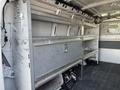 Interior of a 2014 Chevrolet Express van with metal shelving units on both sides and a storage area at the back