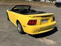 A yellow 2003 Ford Mustang convertible with a black interior and a rear trunk featuring the word Mustang on it