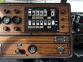 Dashboard controls of a 1991 Sutphen Deluge featuring a wooden panel with various switches gauges and a seatbelt reminder