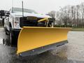 A 2023 Ford F-250 with a yellow snow plow attachment in the foreground
