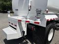A 2015 Ford F-750 truck with a large water tank and white utility attachment on the back featuring two silver fittings and red and white reflective stripes