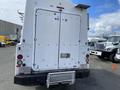 A 2015 Ford F-550 with a white rear, featuring double doors with handles and safety lights mounted on the tailgate