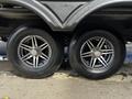 Two metallic rims with shiny five-spoke designs and black tires are positioned closely together on the underside of a vehicle