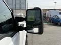 A 2011 Ford F-350 SD's side mirror with a partially visible reflection in the smaller mirror